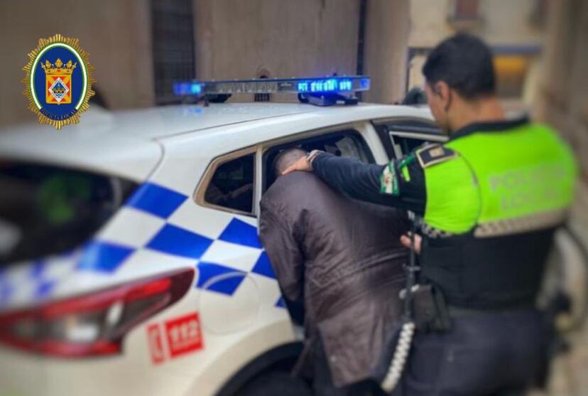 Un policía local introduce en el coche al detenido por agreder a su pareja en la calle.