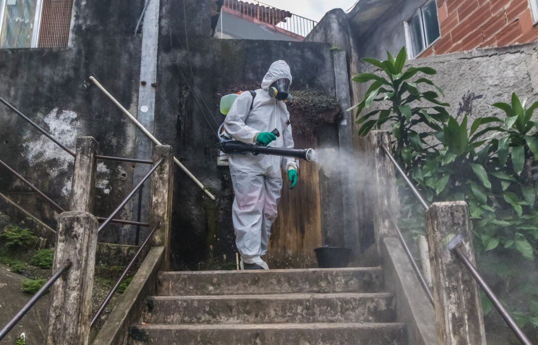 Un trabajador realiza labores de desinfección en una favela de Brasil durante la pandemia