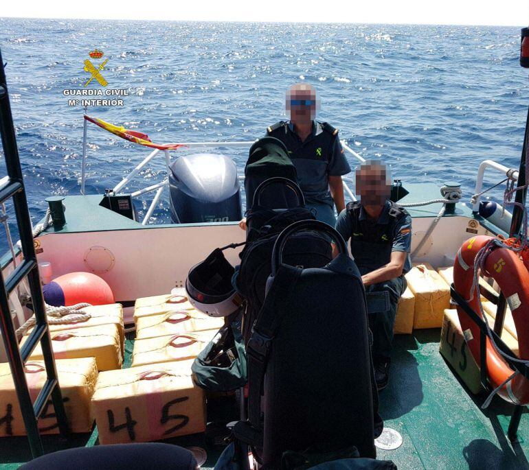 Agentes de la Guardia Civil de Huelva con los fardos de hachís incautados en el mar. 