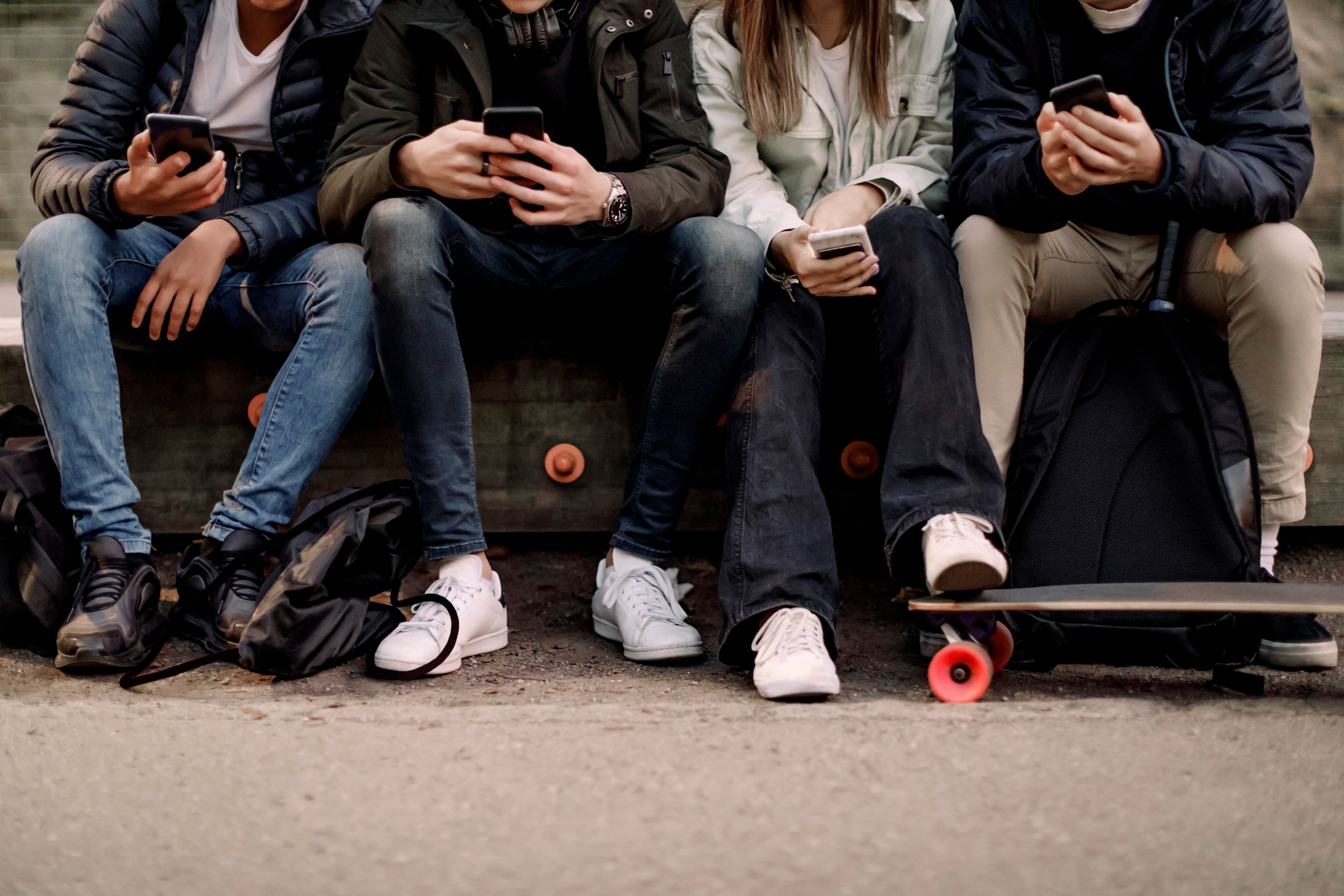 Un grupo de adolescentes consultan su teléfono móvil.