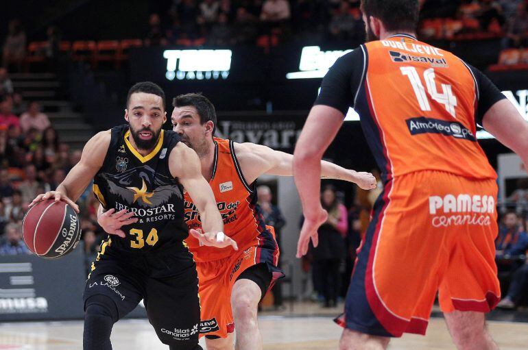 El base estadounidense de Iberostar Tenerife Davin White (i) avanza con el balón perseguido por Rafa Martínez, del Valencia Basket,, durante el partido de Liga ACB que se juega esta tarde en el pabellón Fuente de San Luis, en Valencia.