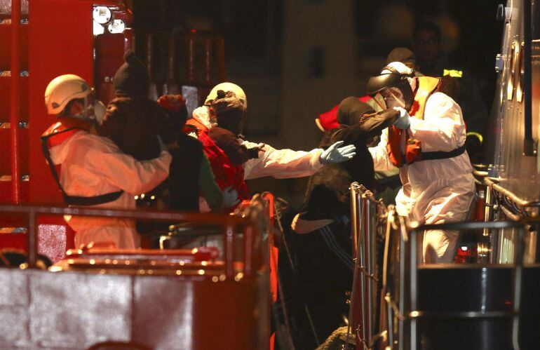 Miembros de Salvamento Marítimo ayudan a desembarcar a los 26 inmigrantes rescatados en alta mar.