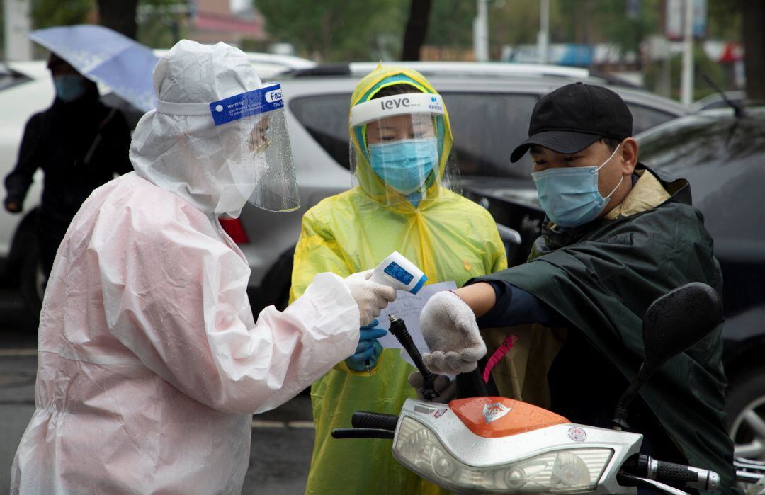 Trabajadores del servicio de salud chino toman la temperatura a conductores en la ciudad de Jilin.