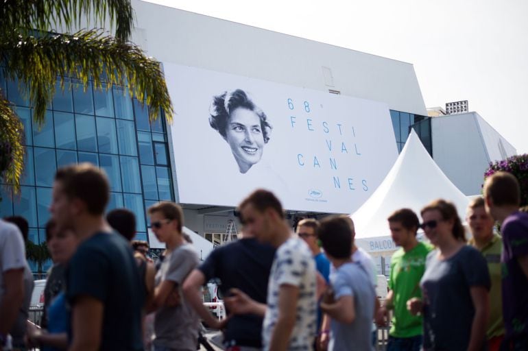 People pass by the official poster of the 68th Cannes Film Festival on the Festivals palace facade in Cannes, southeastern France, on May 11, 2015. AFP PHOTO / BERTRAND LANGLOIS