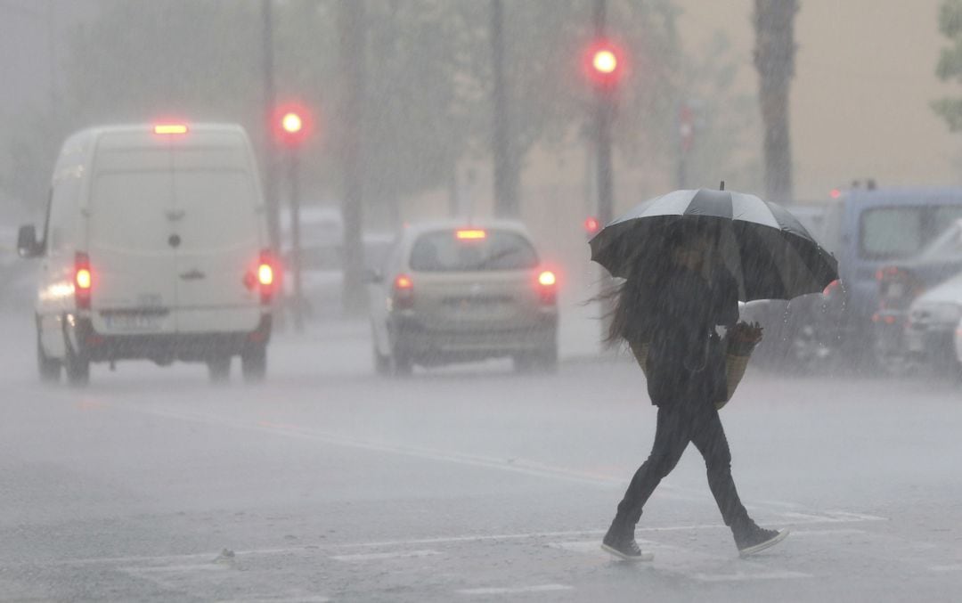 Una persona cruza la calle en un día de lluvia