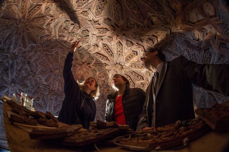 Una restauradora, a la izquierda, muestra los trabajos que realizan en una cúpula del Patio de los Leones a la delegada del Gobierno andaluz en Granada, Sandra García; y al director del Patronato de la Alhambra, Reynaldo Fernández