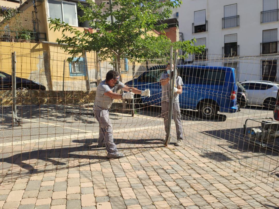 Operarios proceden a retirar la valla de un antiguo solar en el casco histórico de Lorca, cercano a la Colegiata de San Patricio.