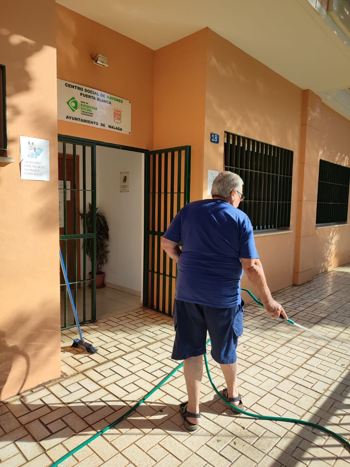 Un vecino limpia la entrada del Hogar del Jubilado en Puerta Blanca