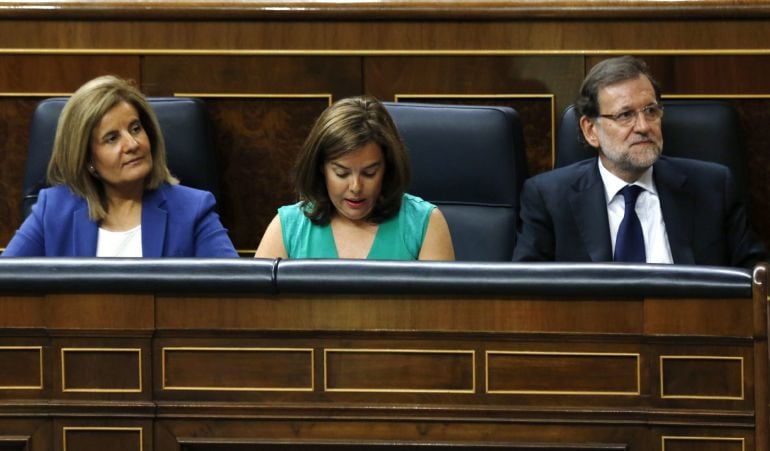 El presidente del Gobierno, Mariano Rajoy (d), junto a la vicepresidenta, Soraya Sáenz de Santamaría (c), y la ministra de Empleo, Fátima Báñez (i)