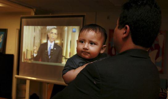 Christian Ramirez holds his nine-month old son Diego while watching President Barack Obama&#039;s White House speech on immigration at a viewing party at Alliance San Diego in San Diego, California November 20, 2014. Obama imposed the most sweeping immigration