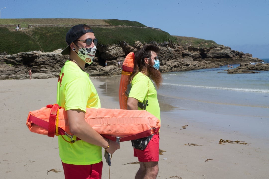 Dos socorristas protegidos con mascarilla vigilan la Playa de A Rapadoira en Foz, en la comarca de A Mariña, Lugo