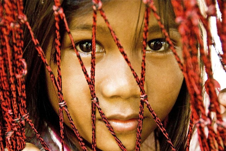 GRA553. PHNOM PENH (CAMBOYA), 04/11/2015.- Fotografía que forma parte de la exposición &quot;Cara a Cara&quot; en la que una niña mira a través de las cuerdas de una hamaca en Kum Rieng, en una zona controlada por el Jemer Rojo hasta 1999 y a la que ahora llega el trabajo social del sacerdote Enrique Figaredo, cerca de la frontera con Tailandia, en el noroeste de Camboya. El periodista Josep Maria San Saturnino, &quot;Sansa&quot;, presenta hasta fin de mes una exposición fotográfica en Phnom Penh sobre el trabajo social de la prefectura del sacerdote asturiano Enrique Figaredo, en la provincia de Battambang, en el noroeste de Camboya. EFE/Josep María San Saturnino ***SOLO USO EDITORIAL***