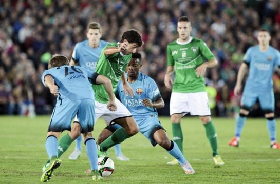 El centrocampista del Villanovense, Curro, intenta llevarse el balón ante los jugadores del F. C. Barcelona, el camerunés Wilfrid Kaptoum y Sergi Samper