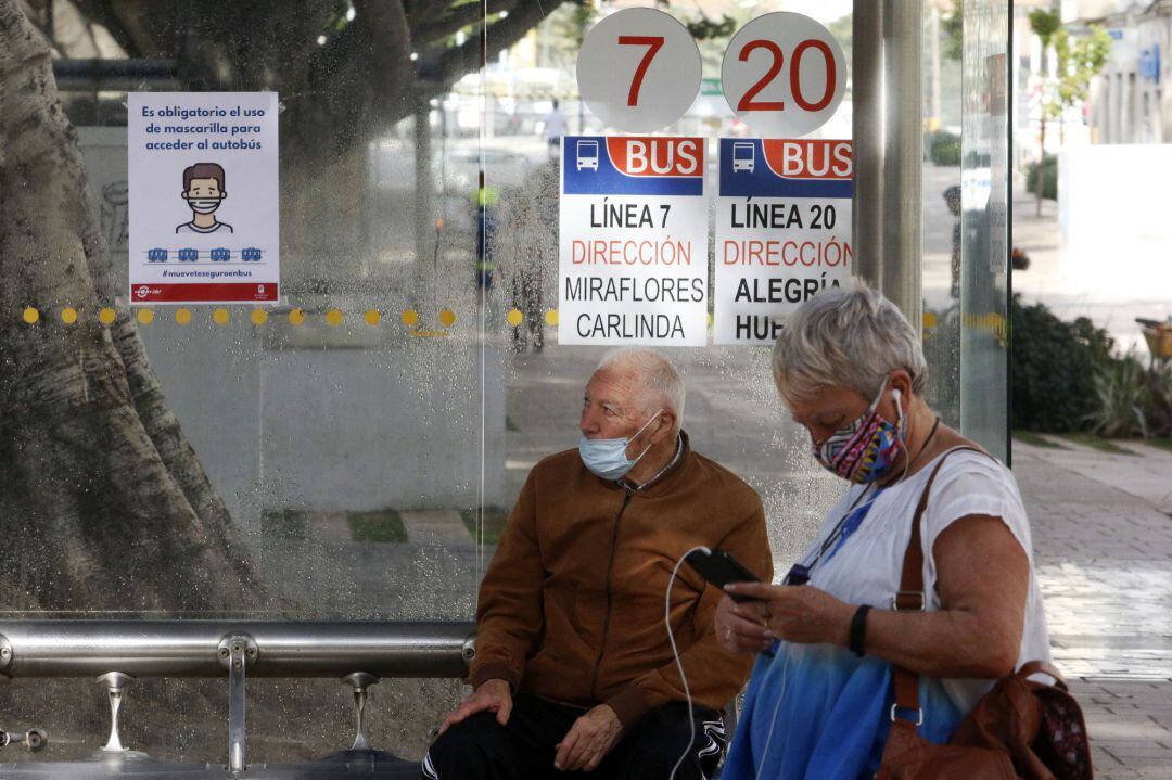 Dos personas esperan el autobús protegido con mascarilla. En Málaga(Andalucía, España), a 04 de mayo de 2020.