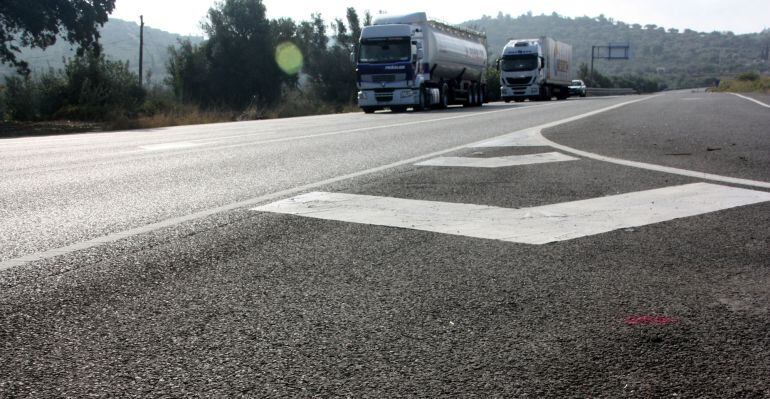 Primer pla de les pintades a l'asfalt de les obres de la nova rotonda del Perelló mentre passen els camions per l'N-340. Imatge del 9 de novembre de 2015. (horitzontal)