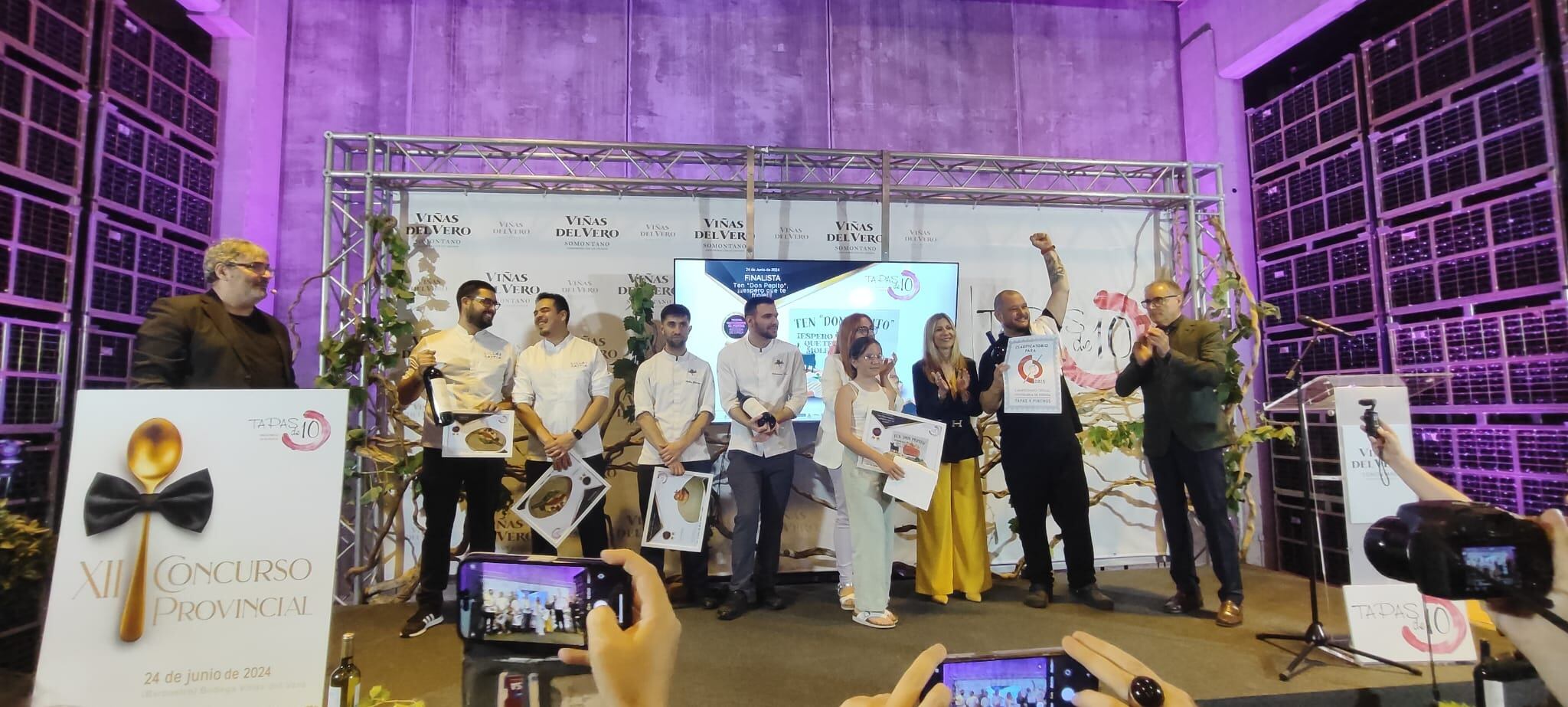 Los ganadores del XII Concurso Provincial de Tapas -Ramón Lapuyade, con el brazo en alto- posan en el escenario de la gala, que se celebró en la bodega de Viñas del Vero, en el Somontano.