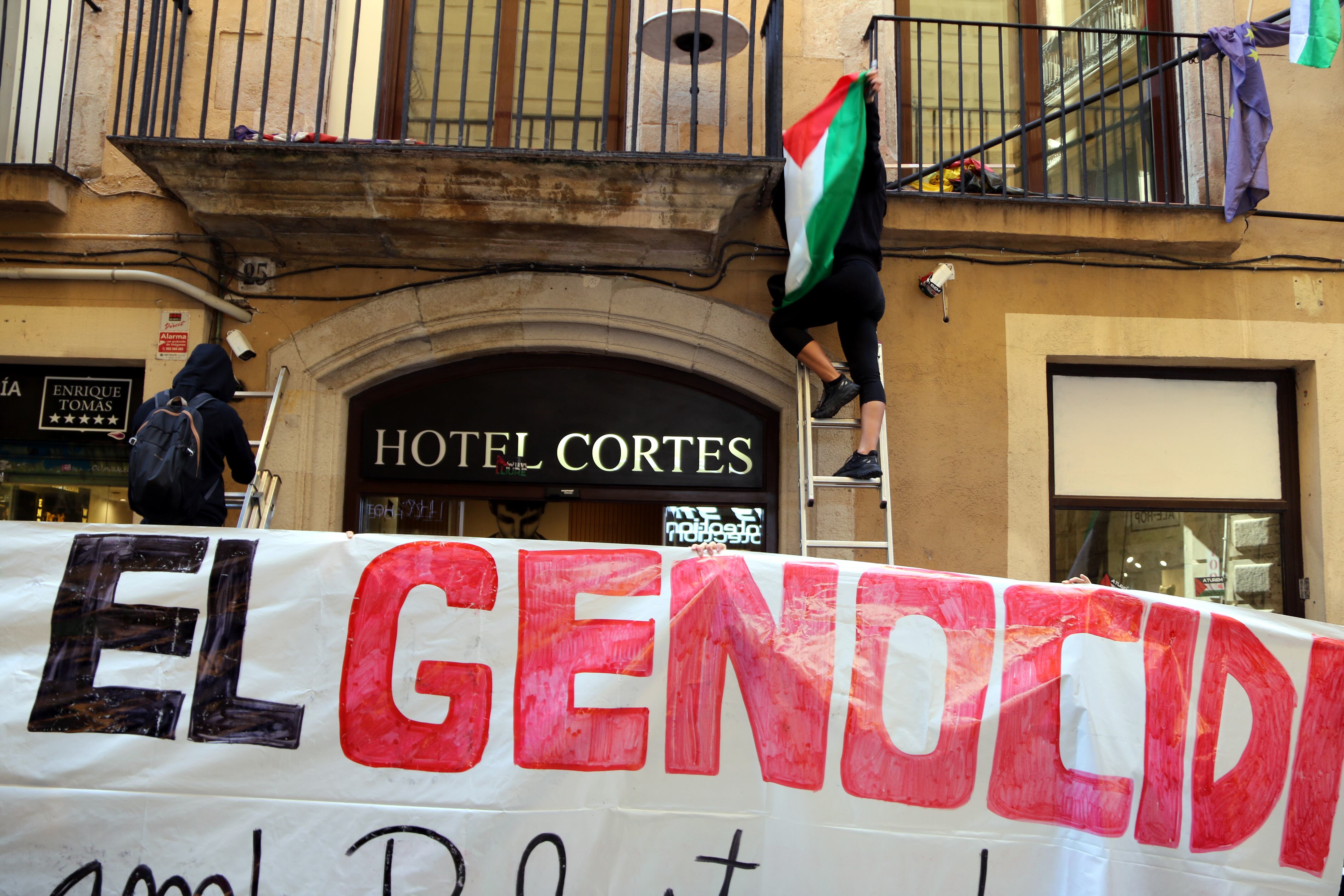 Activistes pengen una bandera palestina a l'Hotel Cortés del carrer Santa Anna de Barcelona.