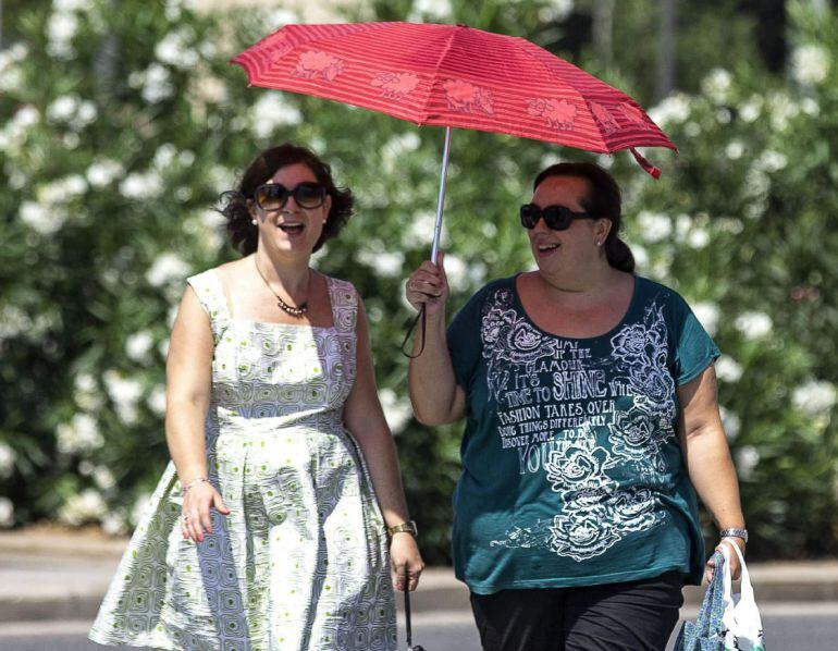 GRA092. VALENCIA, 24/07/2015. Dos mujeres se protegen del intenso calor bajo un paraguas mientras pasean por la Ciudad de las Arte y las Ciencias de Valencia. Hoy se espera una subida de las temperaturas en la provincia de Valencia con máximas que podrían superar los 38º en el interior. EFE/Manuel Bruque.