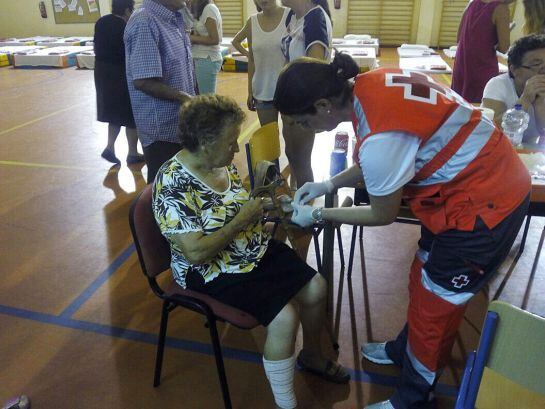 Miembros de la cruz roja atienden a una de las vecinas ubicada en un gimnasio del centro escolar de Castell de Ferro, debido al incendio forestal declarado en la Sierra granadina de Lújar.