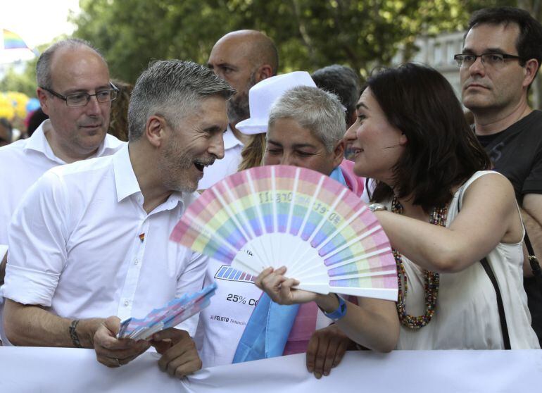 El ministro del Interior, Fernando Grande-Marlaska (i), y la ministra de Sanidad, Carmen Montón (d), conversan durante la manifestación del Orgullo 