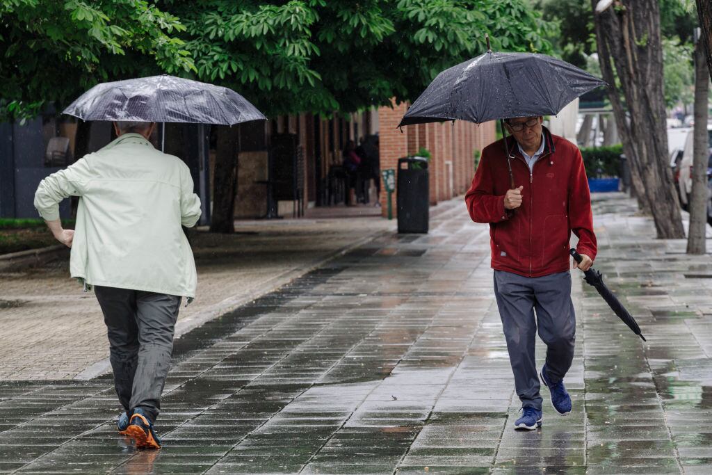 Dos personas pasean bajo la lluvia.