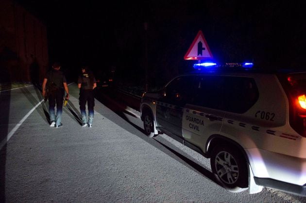 Dos agentes de la Guardia Civil cortan la carretera que da acceso al lugar en el que un hombre lleva atrincherado desde las 21:00 horas del martes.