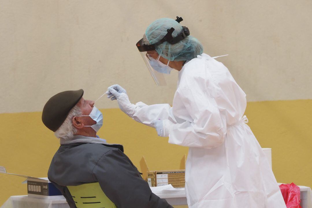 Una sanitaria toma muestras a un hombre a través de un frotis de nariz durante la realización de test de antígenos a los vecinos, en una imagen de archivo