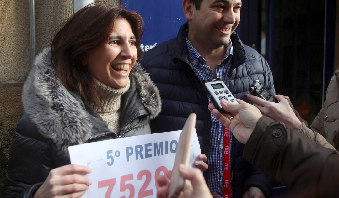 Carlos y Sara, propietarios de la administración de Lotería situada en la calle de El Collado de Soria, celebran haber vendido íntegramente el 75206, el primer quinto premio del Sorteo de Lotería de Navidad