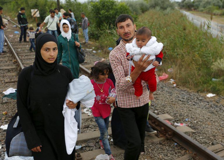 Una familia de refugiados sirios camina por la vía del tren que cruza entre Serbia y Hungría.