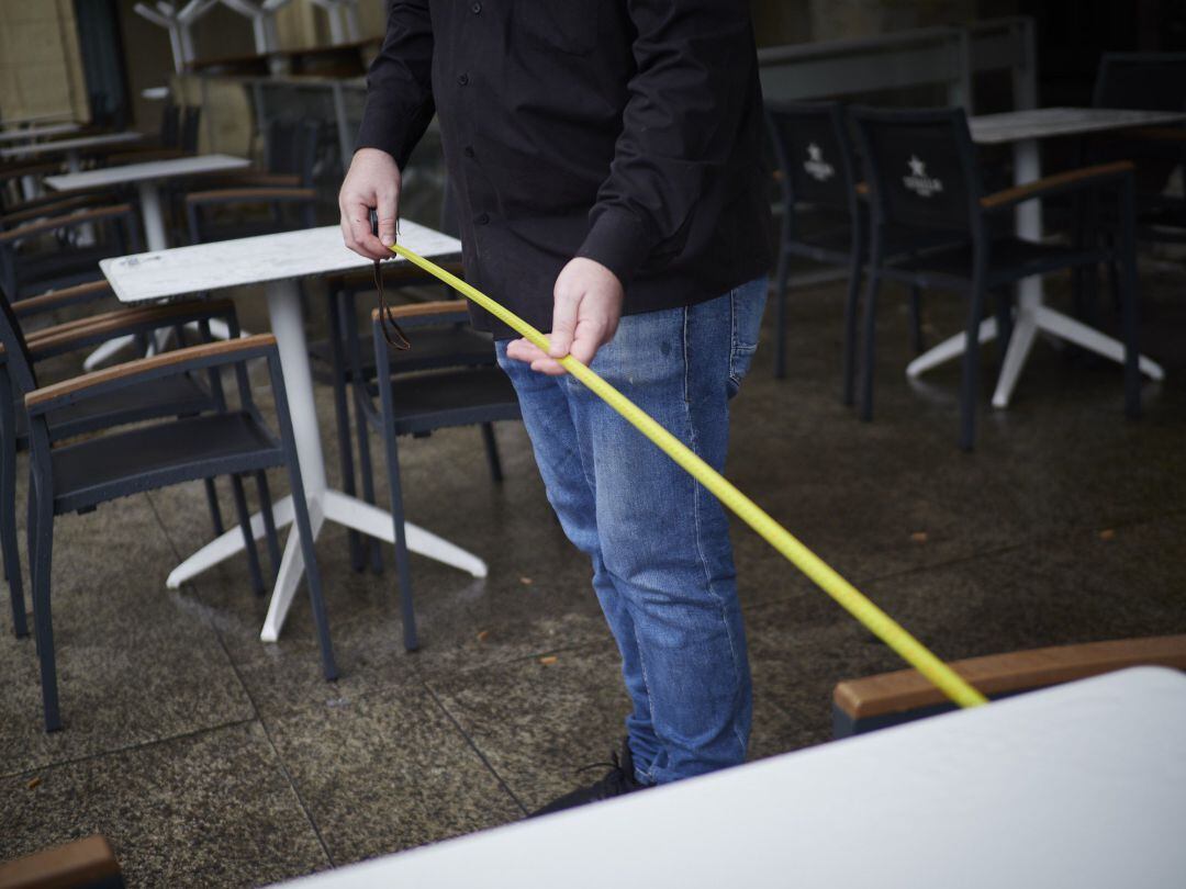 Camarero de una terraza de Pamplona utiliza un metro para asegurarse de que las medidas de distanciamiento son las correctas.