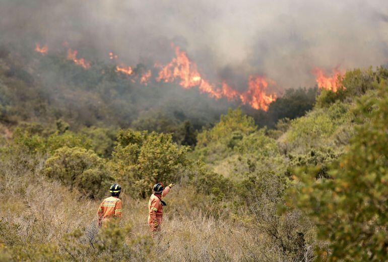 Dos bomberos observan las llamas de un incendio