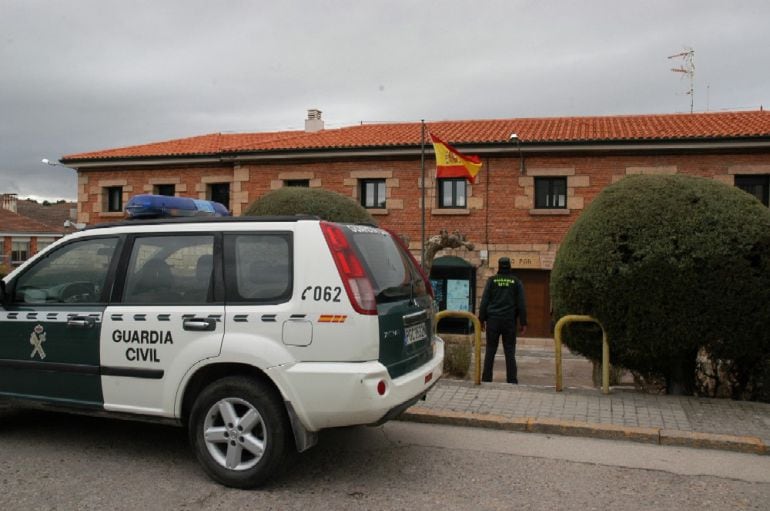 Un vehículo y un agente de la Guardia Civil ante un cuartel