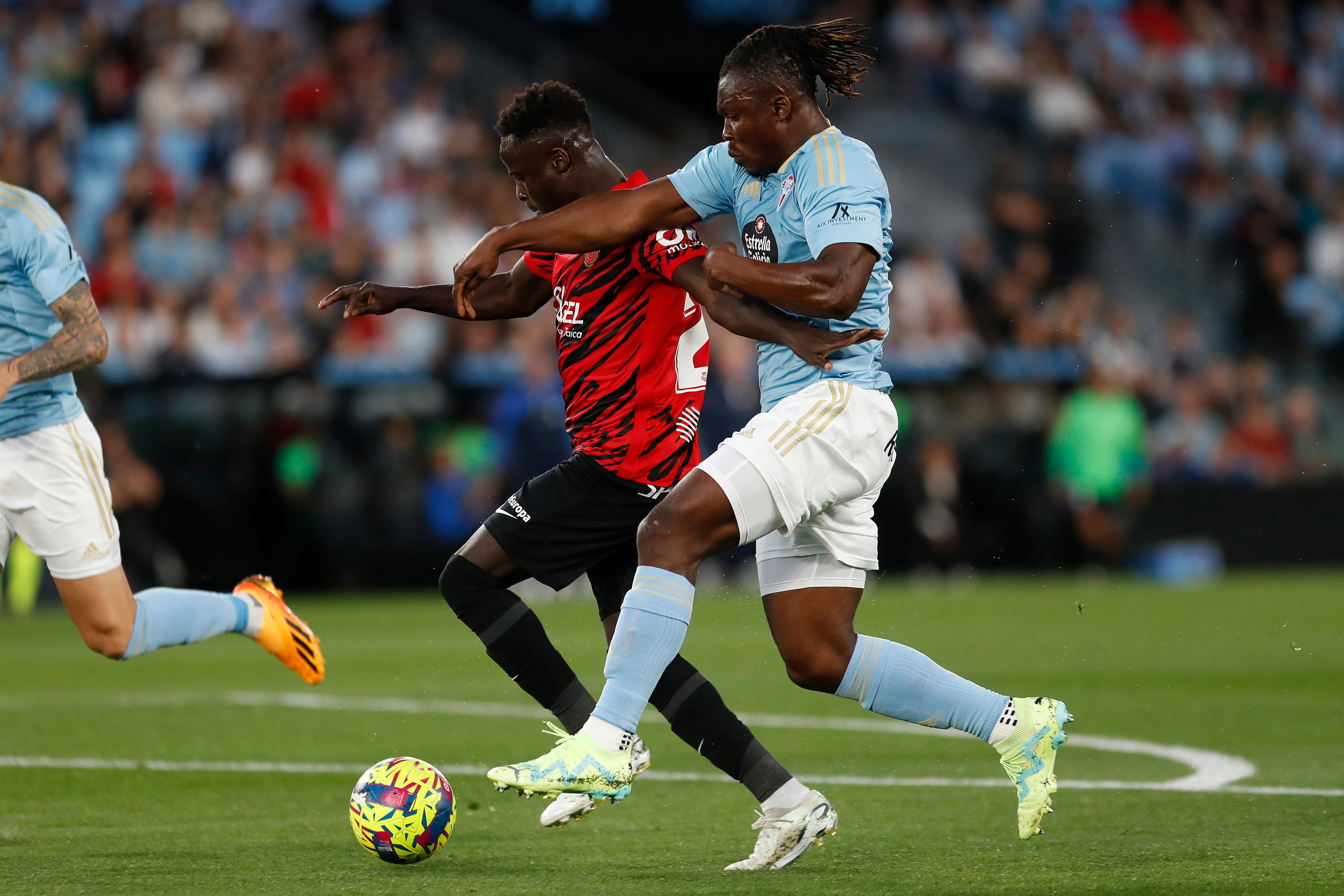 Vigo (Pontevedra),17/04/2023.- El defensa ghanés del Celta de Vigo, Joseph Aidoo (d) disputa una posesión con Amath Ndiaye (i) delantero senegalés del Mallorca, durante el encuentro correspondiente a la jornada 29 de primera división disputado hoy lunes en el estadio de Balaidos, en Vigo. EFE / Salvador Sas.
