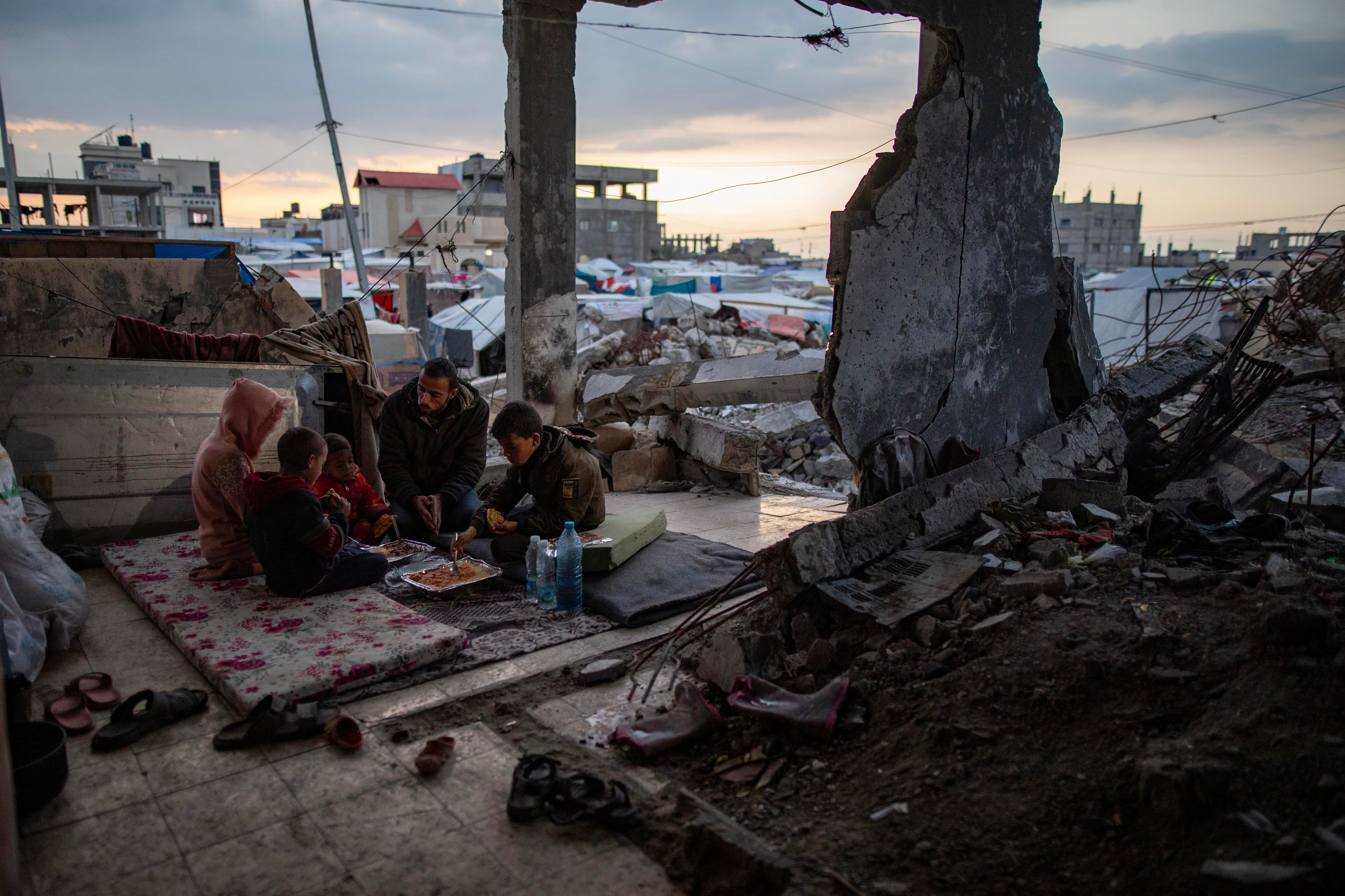 Una familia se prepara para romper el ayuno del Ramadán en una casa destruida en Rafá (Gaza).