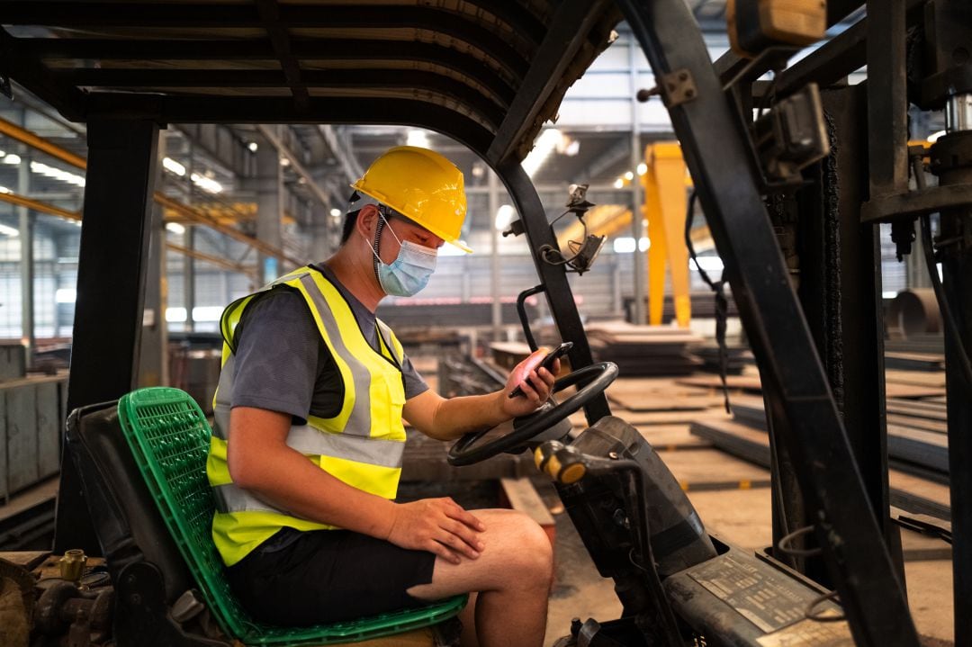Un operario consulta su teléfono en su trabajo.
