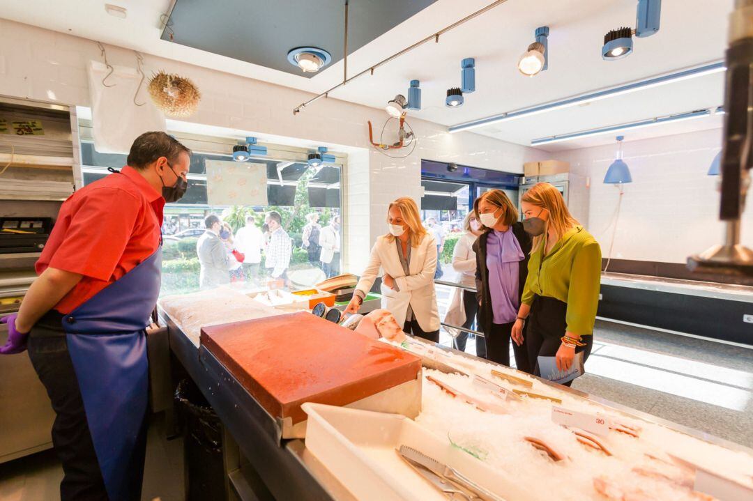 Ana Camins (i), secretaria general del PP de Madrid, la senadora Paloma Adrados (c) y Noelia Núñez, portavoz local, durante su visita a una pescadería de Fuenlabrada.