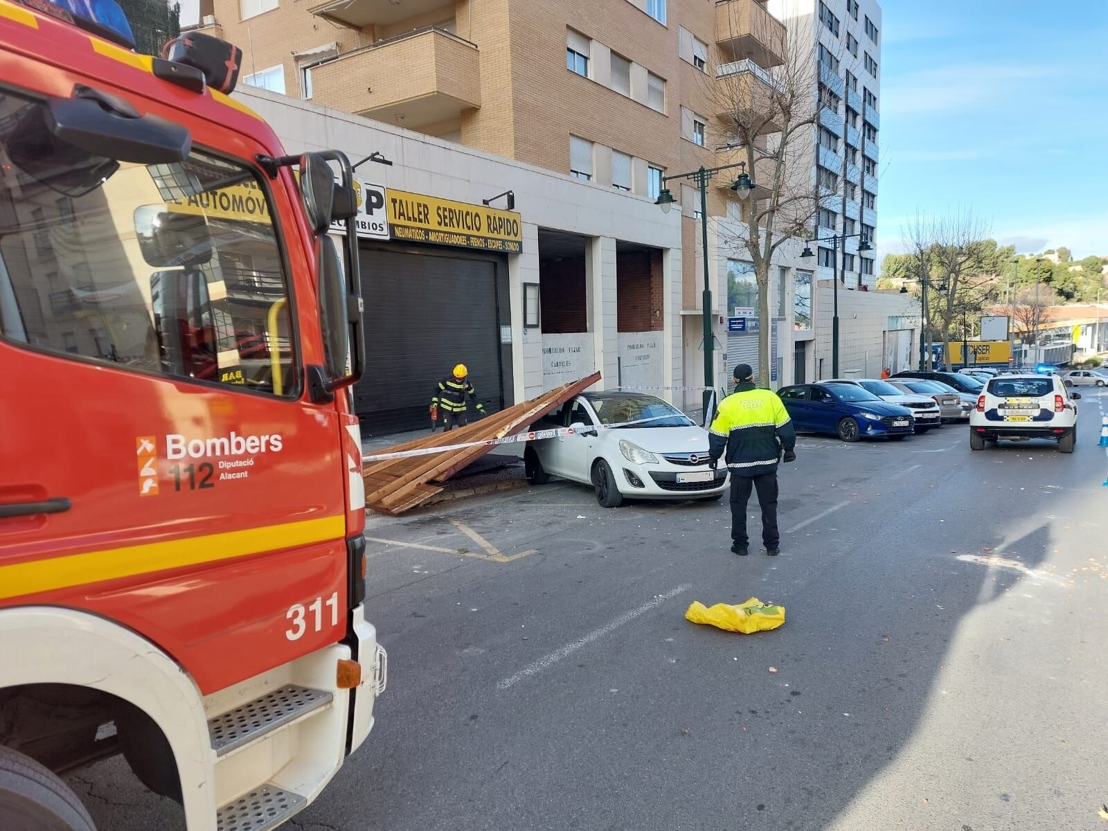 Los bomberos y Policía Local atendiendo una de las incidencias a causa del viento en la calle Valencia de Alcoy.