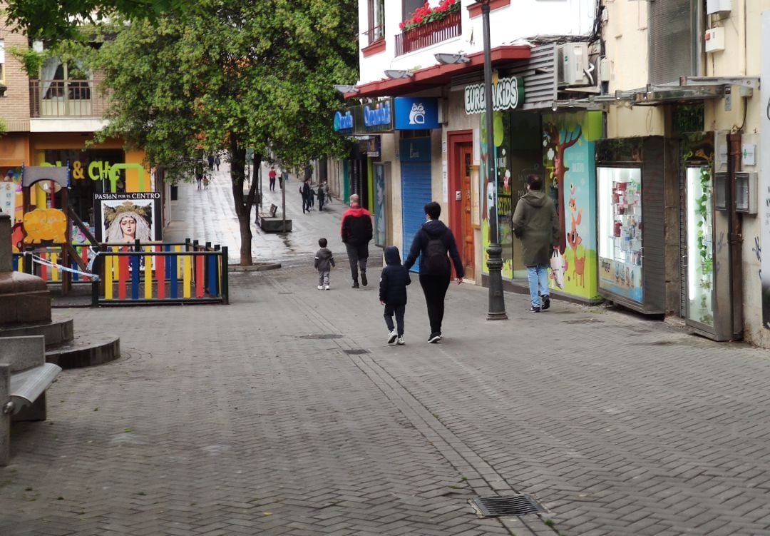 Dos padres con sus hijos pasan por el parque clausurado que hay en la Plaza de los Jardinillos.