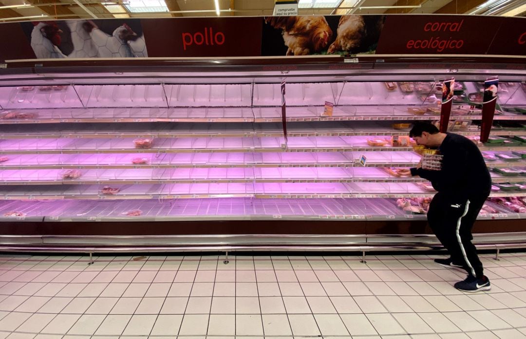 Un hombre coge productos en los refrigeradores de un supermercado de Madrid pocos minutos después de la declaración del Estado de Alarma que ha hecho el presidente del Gobierno, Pedro Sánchez, ante el avance del coronavirus, en Madrid (España), a 13 de marzo de 2020. 