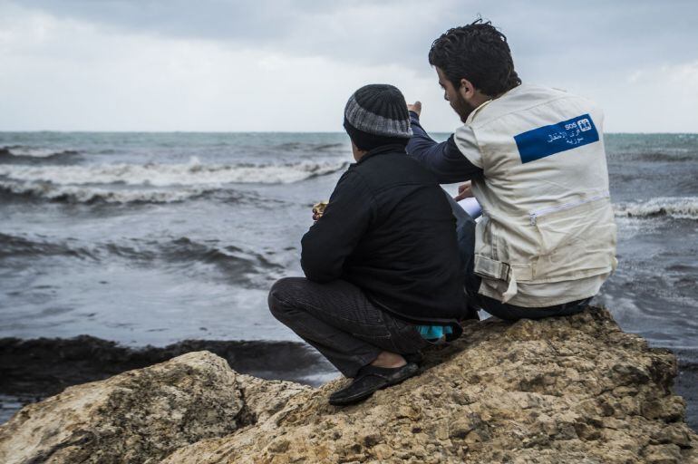 Un trabajador de Aldeas Infantiles habla con un menor frente al mar