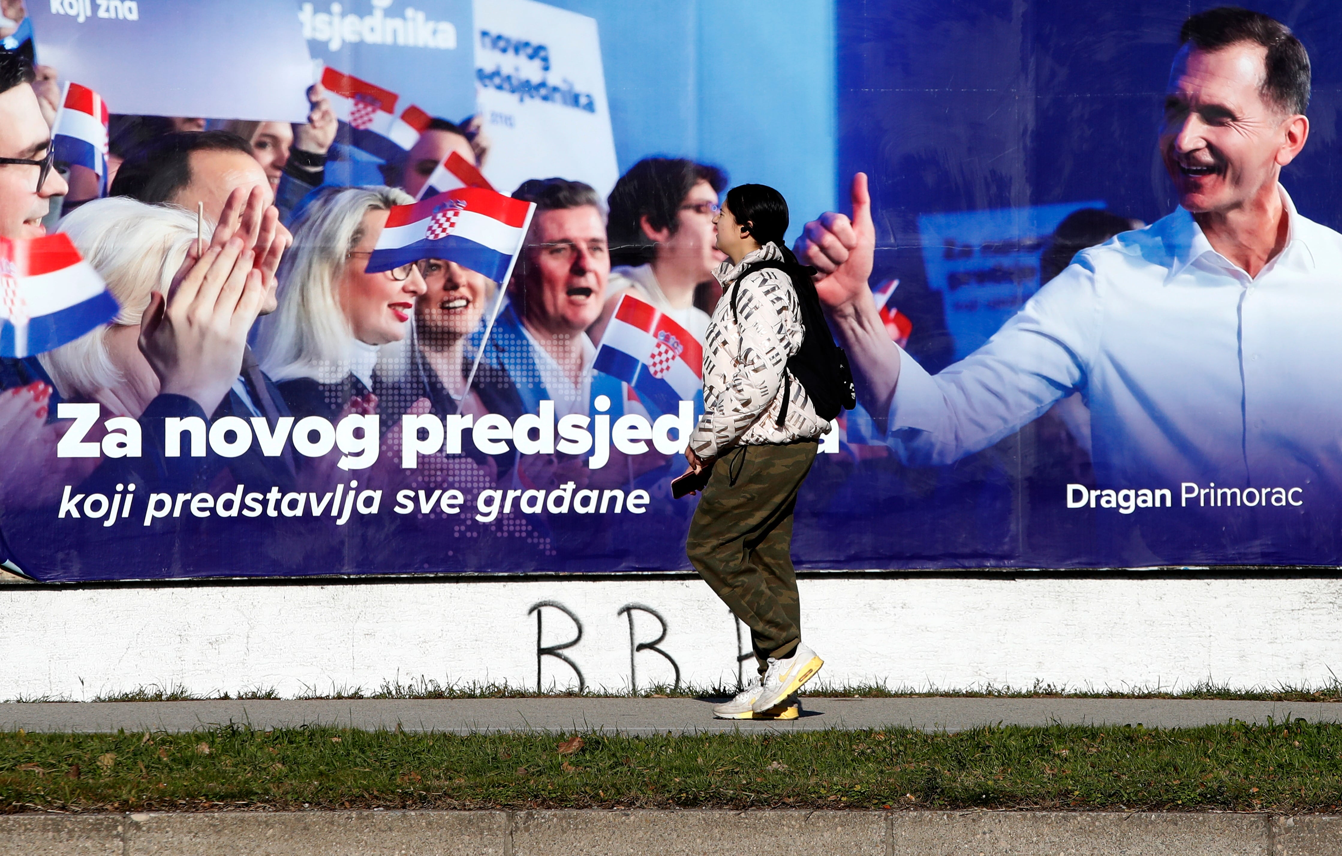 Una mujer pasa por delante de un cartel electoral en Zagreb.