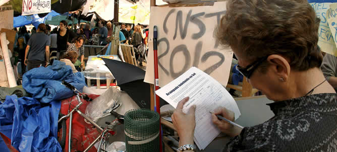 Una mujer deposita su firma en el campamento levantado en la Puerta del Sol de Madrid para apoyar la acampada que se ha organizado allí, prevista hasta el próximo domingo 22 de mayo, día de las elecciones autonómicas y locales.