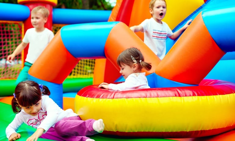 Imagen de un grupo de niños jugando en un castillo hinchable. 