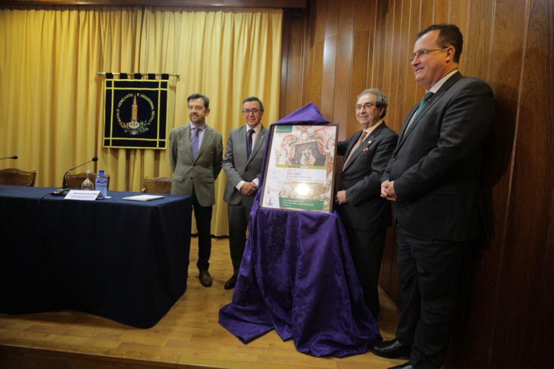 De izquierda a derecha, Joaquín Rodríguez, comisario de la exposición; Práxedes Sánchez, presidente del Mercantil; José Antonio Fernández Cabrero, hermano mayor de La Macarena; y Juan Carlos Cabrera, delegado municipal de Fiestas Mayores, junto al cartel de la muestra que abrirá la XIV edición del Círculo de Pasión