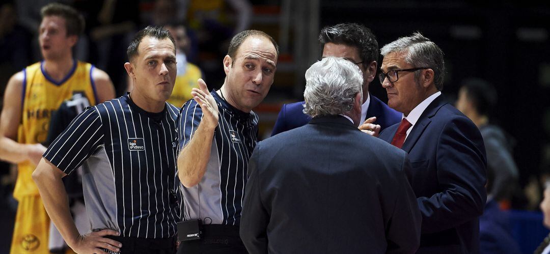 Paco García (d) charla con los arbitros tras la suspensión del partido ante Herbalife Gran Canaria en el &#039;Fernando Martín&#039;