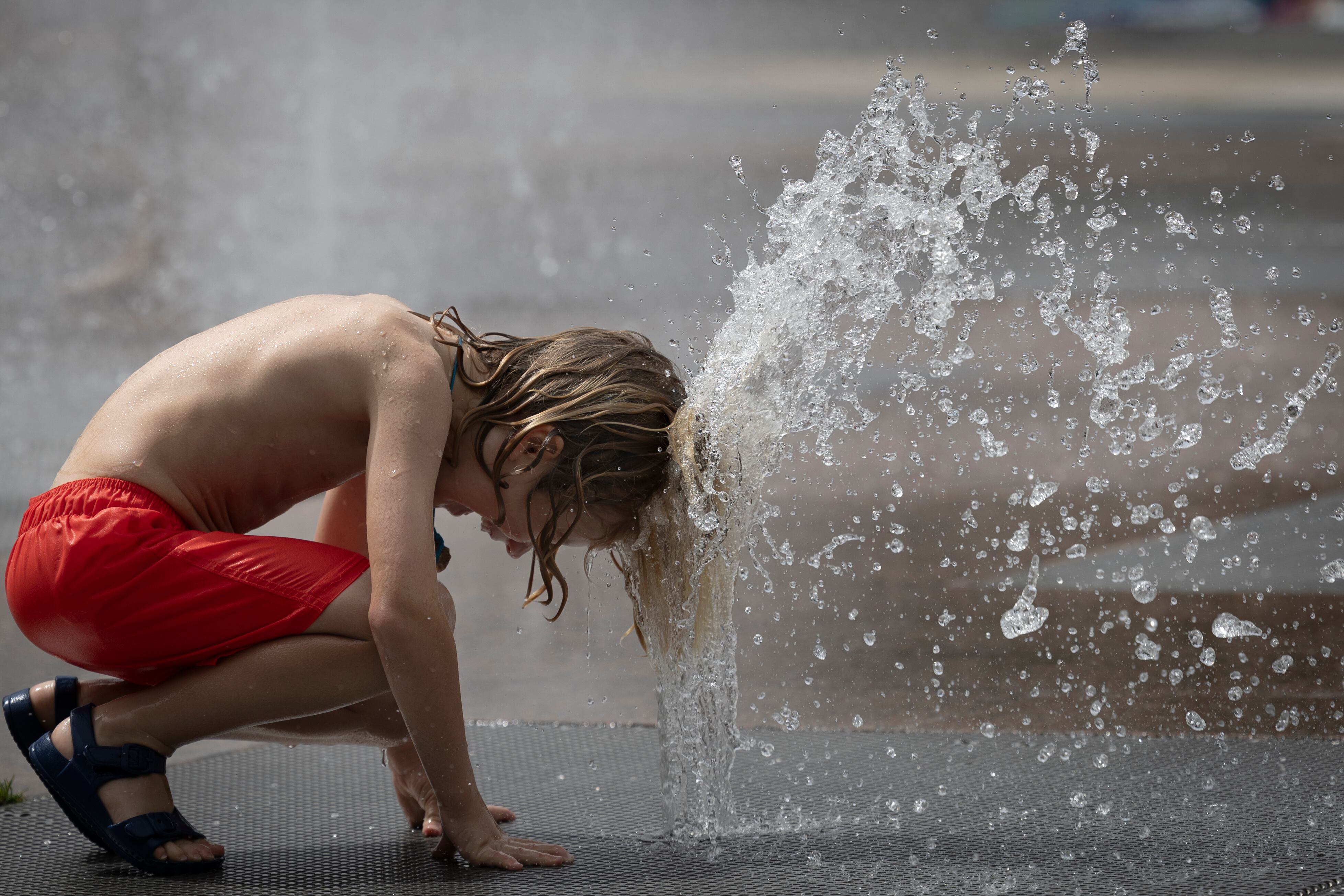 Un niño se refresca en una fuente de Pamplona para huir del calor.