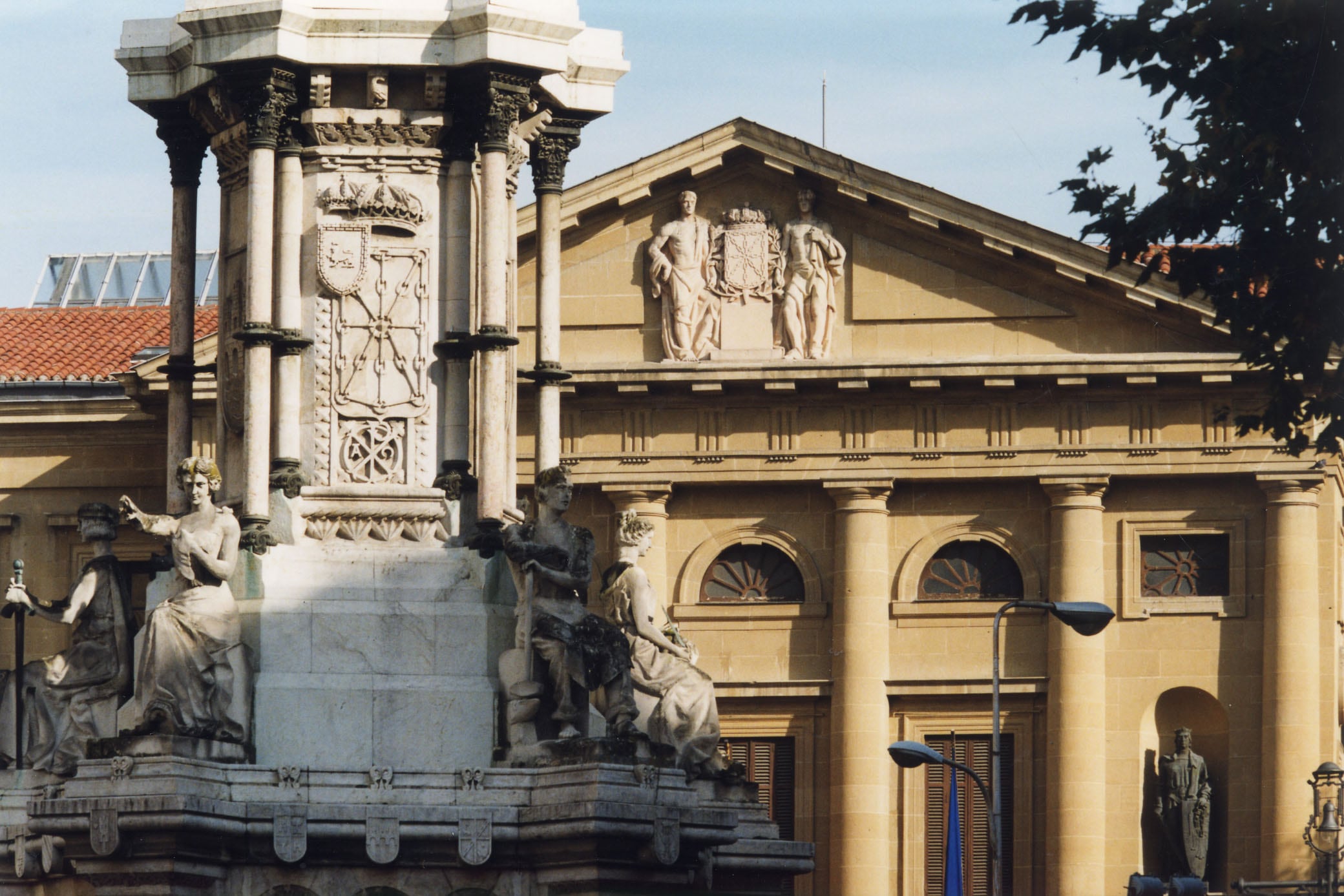 Vista parcial del palacio de Navarra con el monumento a los Fueros en primer término