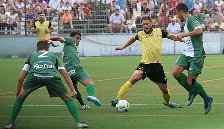 Varios jugadores del Mancha Real intentan quitar un balón a un futbolista del Marbella.