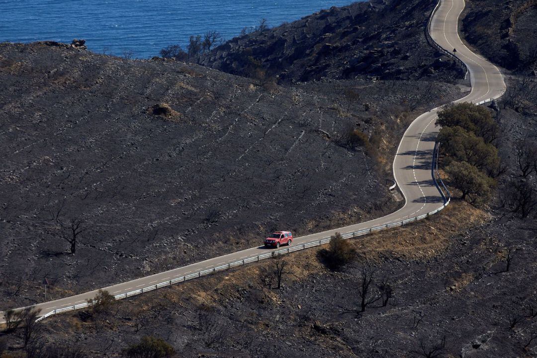  Un automóvil circula por la carretera que discurre por la zona que ha ardido en el incendio que, desde este viernes, afecta al parque natural de Cap de Creus (Girona) y que los Bomberos de la Generalitat han dado por estabilizado este domingo y que, segú