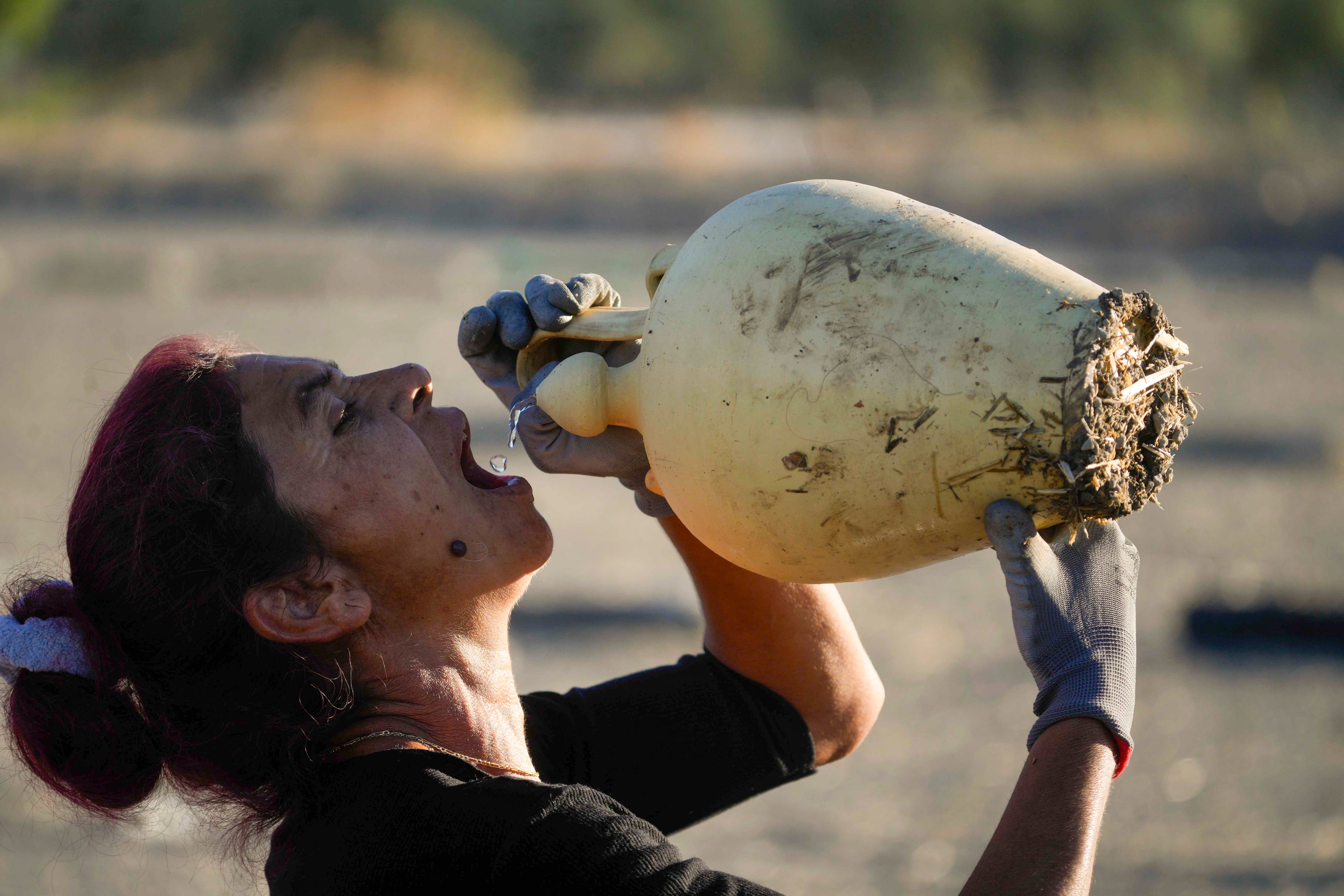 Una trabajadora se refresca bebiendo de un botijo en la localidad cordobesa de Montalbán. EFE/Rafa Alcaide